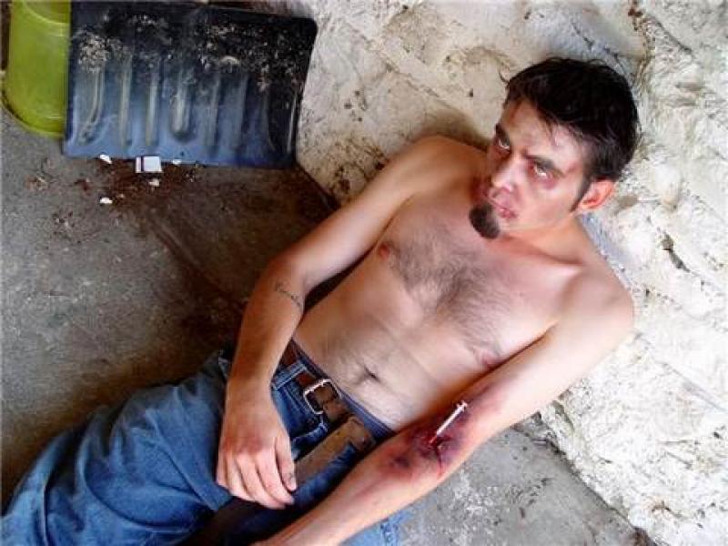 Худой героиновый наркоман со шприцом в руке